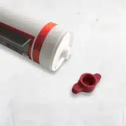 Verschlusskappe für Silikon, rot, neben einer Silikonkartusche mit grafischem Design.